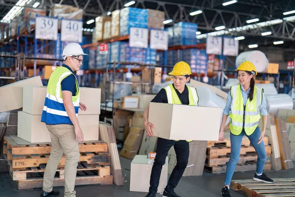 Staff in large storage warehouse together packing goods and carry carton box on pallet