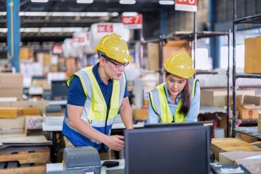 Geniş depo deposunda çalışan personel stajyer öğrenci kutusunu kontrol ediyor ve kasiyeri tarıyor.
