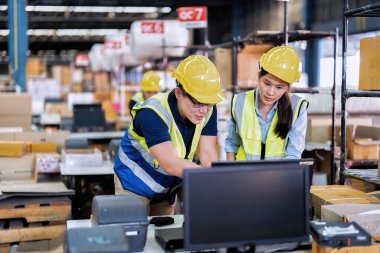 Geniş depo deposunda çalışan personel stajyer öğrenci kutusunu kontrol ediyor ve kasiyeri tarıyor.
