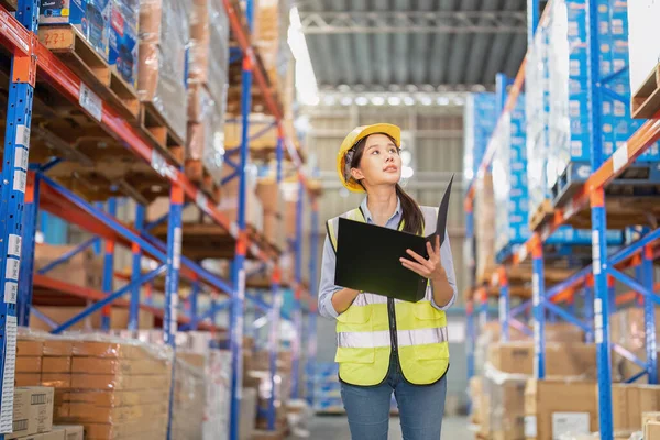 Staff working in large depot storage warehouse hold check list walking check goods on shelf
