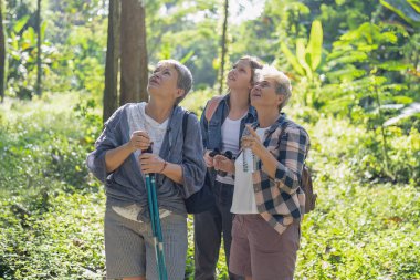 Sırt çantalı turistler, ağaç görünümlü dürbünle gezintiye çıkıyorlar.