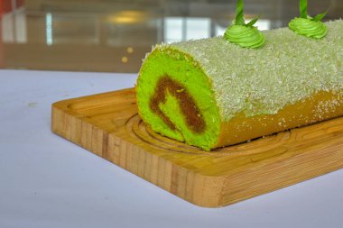 Pandan BOLU pastası çikolata dolgulu ve ahşap tahtaların üstünde hindistan cevizi olan (Endonezya 'da kue bolu pandan denir))