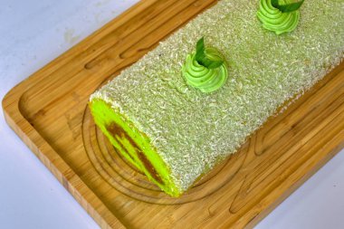 Pandan BOLU pastası çikolata dolgulu ve ahşap tahtaların üstünde hindistan cevizi olan (Endonezya 'da kue bolu pandan denir))
