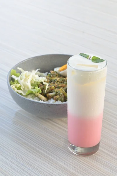 pink lava drink and green chili squid rice with salad on wooden table or in indonesia called nasi cumi cabe ijo (natural light)