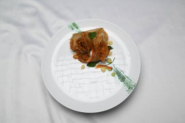 a plate of lumpia spaghetti spring rolls on a white cloth.