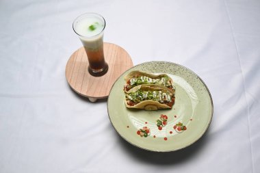 glass of limeng milkshake and a plate of taco eungkot suree on white cloth. 