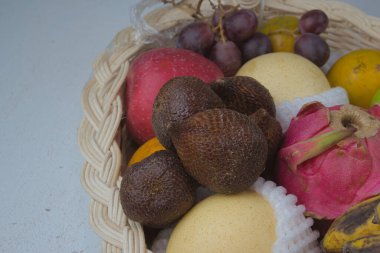 salak fruit among a basket of fresh natural fruits on a white table.