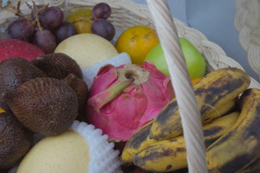 a basket of fresh natural fruits, apples, bananas, dragon fruit, salak, pears, oranges and grapes.