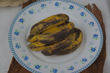 a pile of bananas on a classic white plate.
