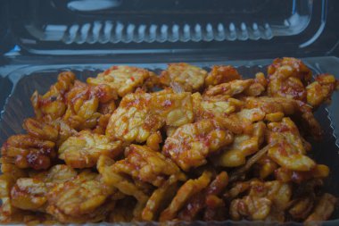 Indonesian food tempe still with its wrapper, black background. tempe goreng sambal.