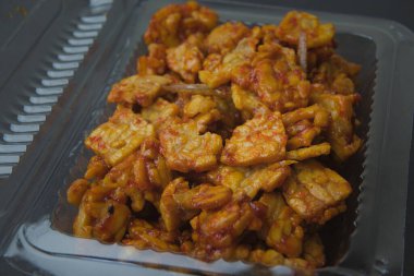 Indonesian food tempe still with its wrapper, black background. tempe goreng sambal.