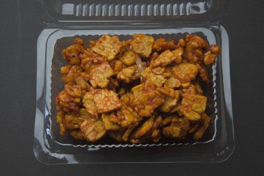 Indonesian food tempe still with its wrapper, black background. tempe goreng sambal.