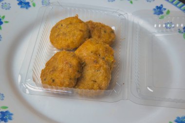 Indonesian food perkedel still with its wrapper on a classic white plate.