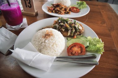 nasi ayam pecak, a serving of pecak chicken rice on a wooden table. natural light.