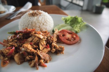 nasi ayam kecombrang, a serving of kecombrang chicken rice on a wooden table. natural light.