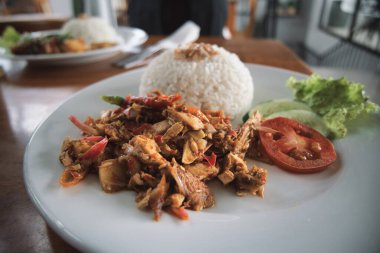 nasi ayam kecombrang, a serving of kecombrang chicken rice on a wooden table. natural light.
