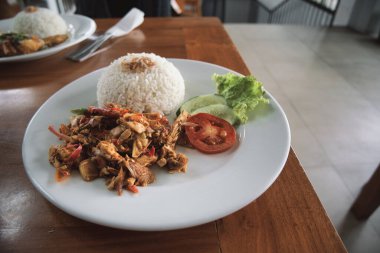 nasi ayam kecombrang, a serving of kecombrang chicken rice on a wooden table. natural light.