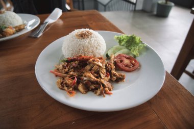 nasi ayam kecombrang, a serving of kecombrang chicken rice on a wooden table. natural light.