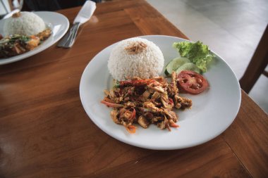 nasi ayam kecombrang, a serving of kecombrang chicken rice on a wooden table. natural light.