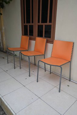 three orange chairs lined up in front of the house.