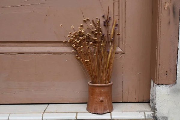 wooden vase with fake flowers and wooden door background.