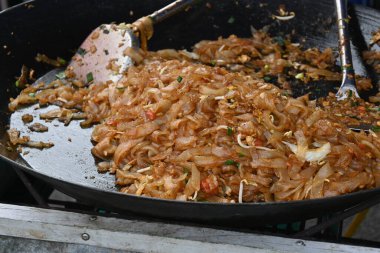 tiau noodles cooked in a large cauldron by street vendors.