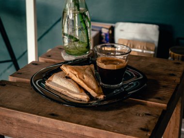 two slices of bread and a glass of coffee on a wooden table for breakfast.