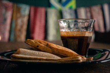 two slices of bread and a glass of coffee on a wooden table for breakfast.