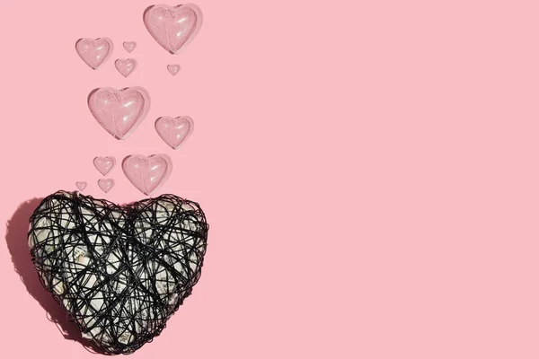 Wire heart with plastic translucent hearts as bubbles on pastel grey background. Minimalist concept.