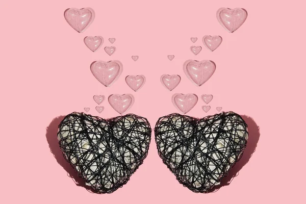 Two wire hearts with plastic translucent hearts as bubbles on pastel grey background. Minimalist Valentine\'s day concept.