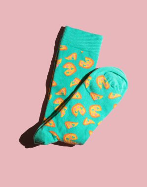 Pastel patterned colourful sock folded in half on pink background. Minimalist concept.