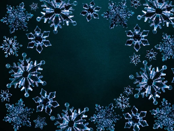 Acrylic plastic snowflakes on a dark emerald green background. Minimal luxury winter natural  wallpaper with creative circle copy space.