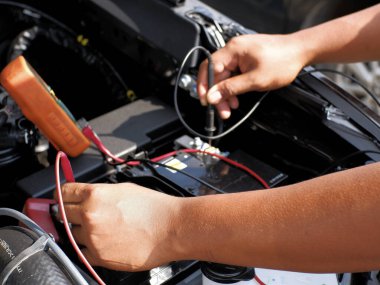 Tamirci akü gerilimini ya da çoklu test cihazını kullanarak arabanın aküsünün durumunu kontrol eder.