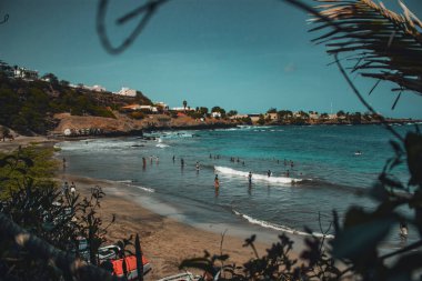 Praia, Ilha de Santiago, Cabo Verde - 2022: 'Kebra Canela' plajı. Santiago 'nun ana plajlarından birinde insanlar ve tekneler var. Üstünde bir kafeden gördüm..