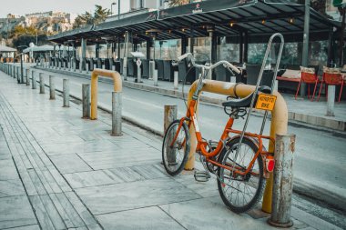 Atina, Yunanistan - 2022: Yunan caddesinde park edilmiş eski turuncu bisiklet. Görüntünün arka planında akropolis.