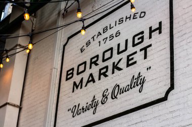 Londra, İngiltere - 2023: 1756 'da bir köprünün altında kurulan ünlü İngiliz sokak pazarının girişindeki borough levhası üzerinde beyaz bir tuğla duvara 