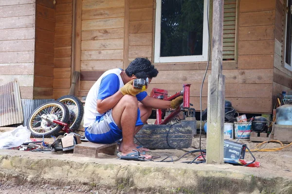 kuaro Doğu Kalimantan, Endonezya 5 Mart 2023: Bir adam bir motosiklet öğütüyor ve monte ediyor