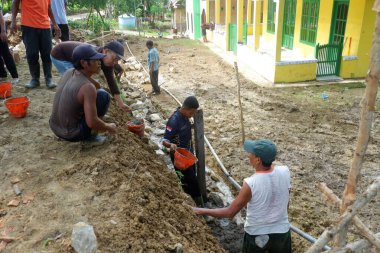 Padang Jaya Köyü sakinleri istinat duvarı inşa etmek için birlikte çalışıyorlar.