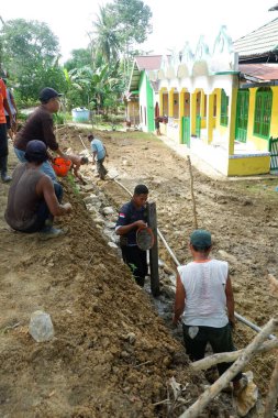  Padang Jaya Köyü sakinleri istinat duvarı inşa etmek için birlikte çalışıyorlar.