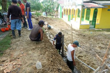  Padang Jaya Köyü sakinleri istinat duvarı inşa etmek için birlikte çalışıyorlar.