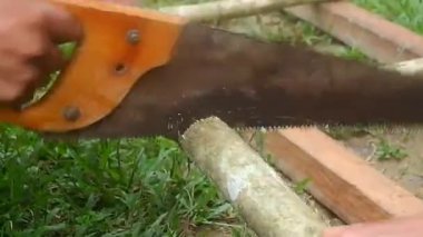 Bir zanaatkarın elleri testereyle odun kesiyor.