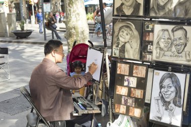 Barselona, İspanya - 5 Ekim 2016: Barselona, Katalonya, İspanya 'daki Ramblas' ta Asyalı sokak ressamı karikatür ve portreler çiziyor ve çiziyor.