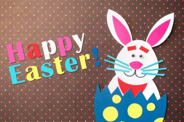 Komik çizgi film tavşanı yumurta ve renkli kartondan yapılmış el yapımı Paskalya bayramlarını kutluyor..