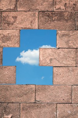 Kahverengi tuğla duvarın ayrıntıları. Arkasında mavi gökyüzünde bir bulut var