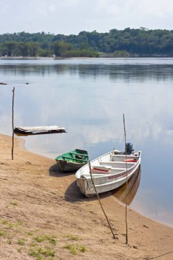 Old wooden boats moored to Amazon river shore in Brazil. The sky reflects on the water. clipart