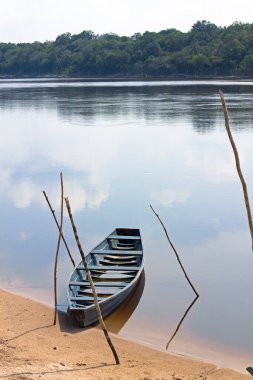 Brezilya 'da Amazon Nehri kıyısına demirlemiş eski ahşap bir tekne. Gökyüzü suyu yansıtıyor..