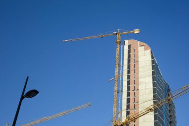 Arkasında mavi gökyüzü olan inşaat halindeki bir otel inşa etmek..