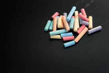 Siyah karatahta üzerinde çok renkli tebeşirler grubu.