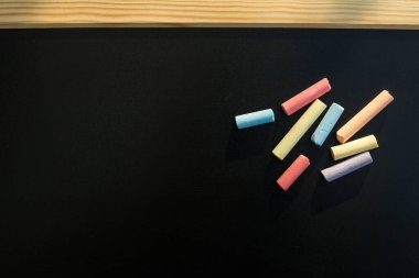 Siyah karatahta üzerinde çok renkli tebeşirler grubu.