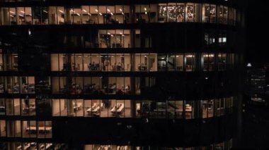 Ofis binasının göz kamaştırıcı hava manzarası. Işıklandırılmış boş ofisler. Geceleri yakın plan parlıyor..